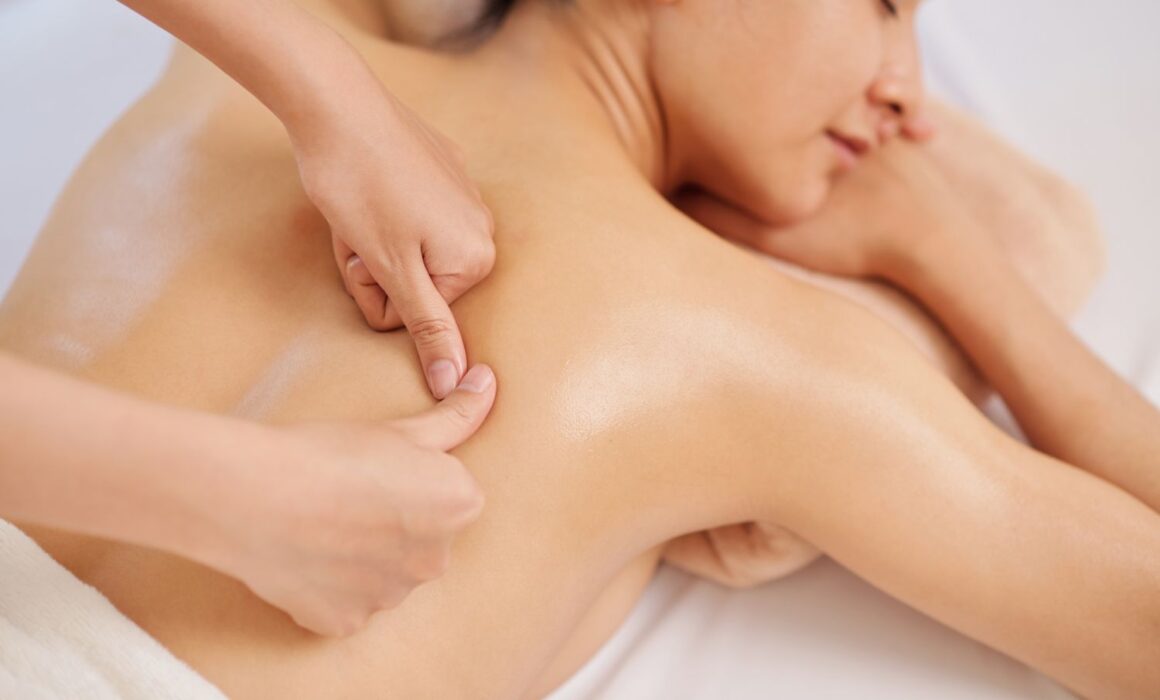 Massage therapist performing deep tissue massage on back to relieve muscle tension